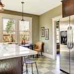 Kitchen with marble top island Olive tone kitchen room with steel refrigerator and marble top kitchen island